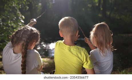 children sit on the banks of river. happy family childhood dream concept lifestyle. a group of little children sit together by the river and talk. kids spend time outdoors in nature in the forest - Powered by Shutterstock