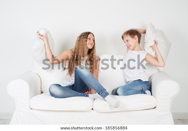 Children sit on the\
couch and pillows\
fighting