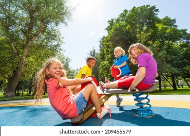 Children Sit On Playground Carousel With Springs