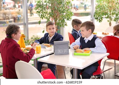 Children Sitting At Cafeteria Table While Eating Lunch