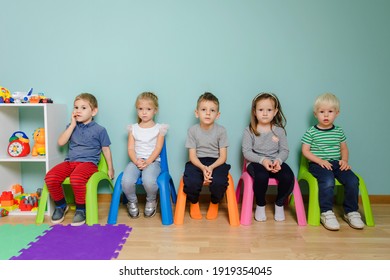 Children are sitting on the colorful chairs in the kindergarten