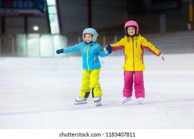 Children Skating On Indoor Ice Rink. Kids And Family Healthy Winter Sport. Boy And Girl With Ice Skates. Active After School Sports Training For Young Child. Snow Fun Activity By Cold Weather.