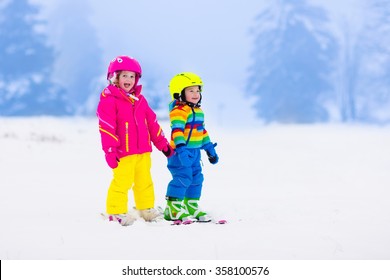 Children Skiing In The Mountains. Toddler Kids In Colorful Suit And Safety Helmet Learning To Ski. Winter Sport For Family With Young Child. Kid Ski Lesson In Alpine School. Snow Fun For Little Skier.