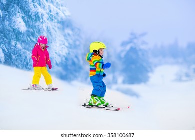 Children Skiing In The Mountains. Toddler Kids In Colorful Suit And Safety Helmet Learning To Ski. Winter Sport For Family With Young Child. Kid Ski Lesson In Alpine School. Snow Fun For Little Skier.