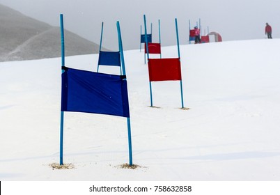 Children Skiing Slalom Racing Track With Blue And Red Gates. Small Ski Race Gates On A Pole With Children Skiing In The Background.