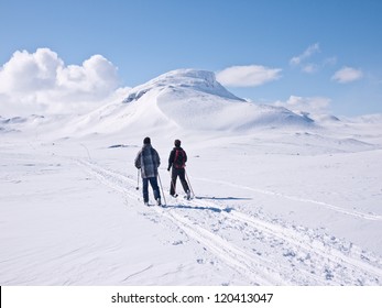 Children skiing towards a mountain pass with a characteristic mountain summit on the right in the norwegian mountains at easter