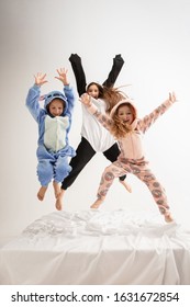 Children in soft warm pajamas colored bright playing at home. Little girls having fun, party, laughting, jumping together, look stylish and happy. Concept of childhood, leisure activity, happiness.