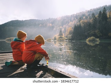 Children Spend Time Outside In Fresh And Cold Air. Small Kids Play In Nature. Healthy Childhood. Family Life Background. Siblings Playing Near By Water In Park Outdoors. Little Friends In Countryside.