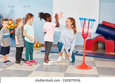 Children And Sports Teacher Make High Five After The Basketball Training In The Gym