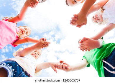 Children standing in a circle holding hands, bottom view