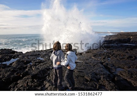 Children standing on the ocean coast, watching waves crashing
