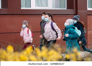 Children students in medical masks leave the school