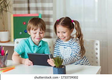 Children Study At Home In During Quarantine Covid-19, Distance Learning Online With A Tablet Computer, A Boy And A Girl Do Their Homework For School. School Children Stayed At Home