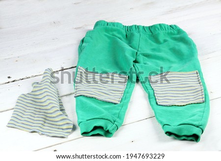 Children sweatpants mended with patches.  Patch with stripes on blue worn sweatsuit.
