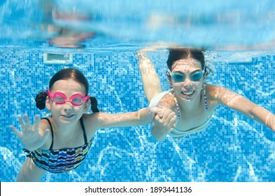 Children swim in swimming pool underwater, little active girls have fun under water, kids fitness and sport on family vacation
