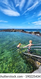 Children Swimming In Rock Pool On Vibrant Summer Day In Kiama, NSW Australia