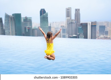 Children Swimming In Roof Top Outdoor Pool On Family Vacation In Singapore. City Skyline From Infinity Pool In Luxury Hotel. Kids Swim And Enjoy Skyscraper View In Asia. Travel With Young Child.