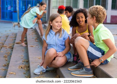 Children talking together while sitting on stairs outdoors. Youngsters chatting during summer day.