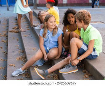 Children talking together while sitting on stairs outdoors. Youngsters chatting during summer day. - Powered by Shutterstock