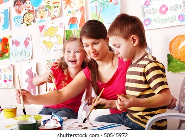 Children  With Teacher Draw Paints In Play Room. Child Care.