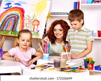 Children with teacher painting at easel in school. - Shutterstock ID 172106699