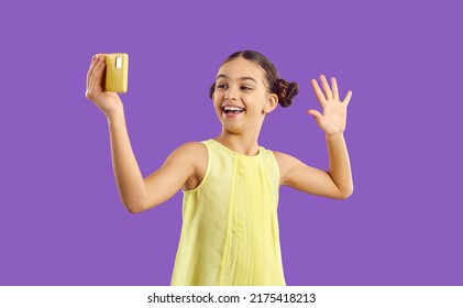 Children And Technology. Cheerful Trendy Kid Girl Influencer Record Video Vlog And Makes Selfie On Purple Background. Funny Cute Preteen Girl Having Fun Waving Hand Looking At Mobile Phone Camera.