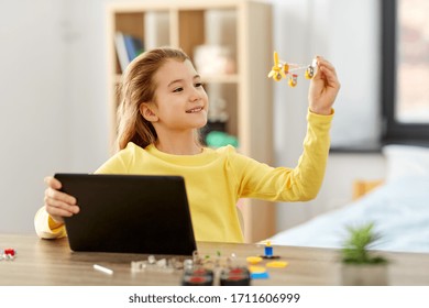 children, technology and science concept - happy girl with tablet pc computer and with robotics kit playing at home - Powered by Shutterstock