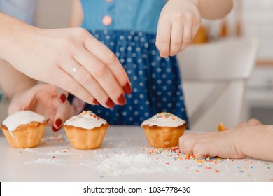 Children with their hands sprinkle cupcakes with colored caramel for Easter. Concept happy family. - Powered by Shutterstock