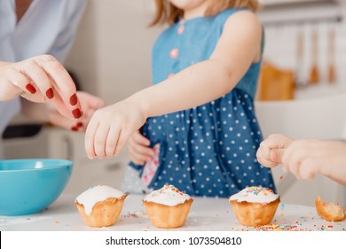 Children with their hands sprinkle cupcakes with colored caramel for Easter. Concept happy family. - Powered by Shutterstock