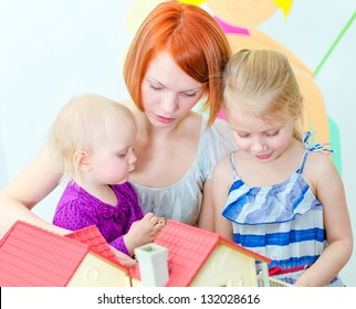 Children And Their Mother Playing With Dollhouse