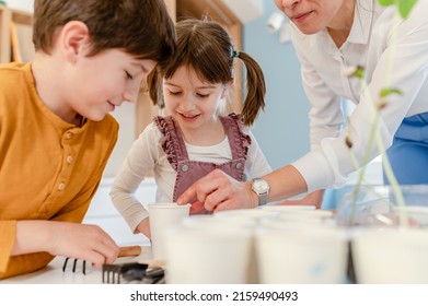 Children With Their Teacher Doing A Science Project With Plants. STEM In Education Concept.