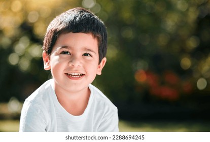 Children, thinking and mockup with a boy in a park or garden, alone outdoor during a summer day. Kids, idea and smile with a happy male child outside in nature for freedom on a blurred background