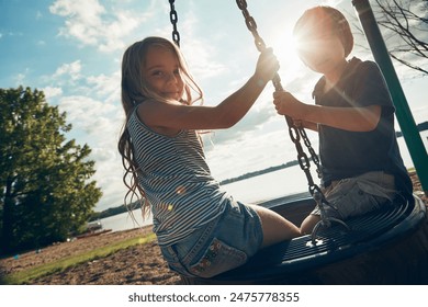 Children, tire swing and portrait in outdoor, bonding and friends at playground for game or adventure. Kids, lens flare and together for fun in backyard or freedom, play and connection on vacation - Powered by Shutterstock