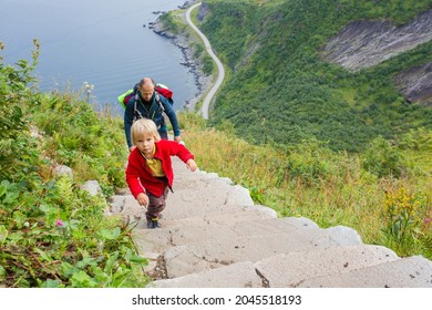 Children, toddler, brothers and father, climbing the stairs to Reinebringen, trekking path leading to the top of the mountain, where one can see Reine village and many fjords from above