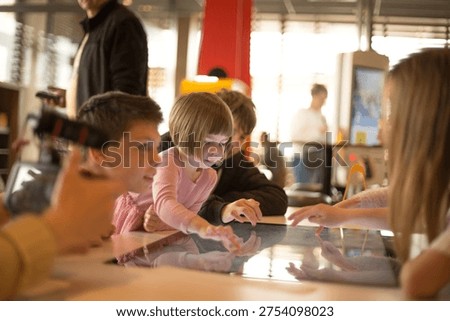 Children touch a large touchscreen table in an educational center, interacting with digital content and learning through playful technology. 