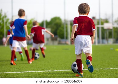 Children Training Soccer On Field. Young Kids Boys Kicking Soccer Football Balls On Grass Pitch. Kids In Sportswear Practice Soccer Skills