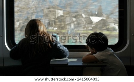 Children traveling by train staring at scenery pass by from a high speed transportation window. Siblings daydreaming and looking at beautiful view