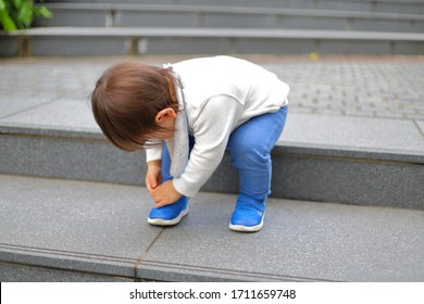 Children Trying To Take Off Their Shoes