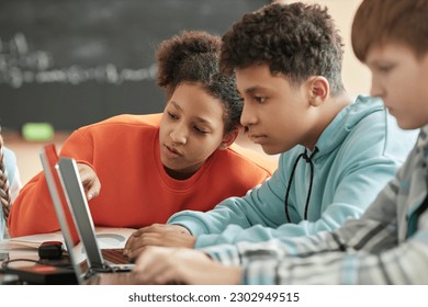 Children using laptop in school classroom focus on black girl looking at computer screen - Powered by Shutterstock