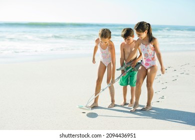 Children Using Metal Detector On Beach