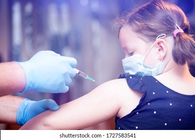 Children vaccinating immunization concept. Doctor injecting vaccination in arm of a little girl with face mask.