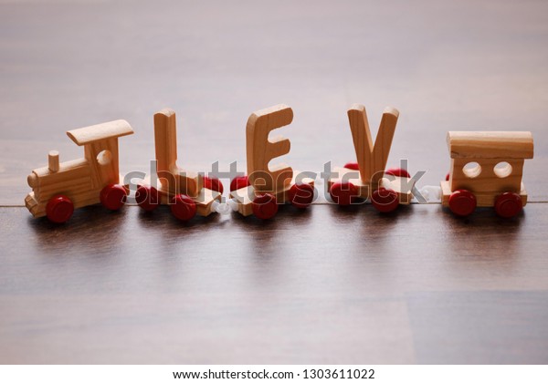 Children\
vintage toy train on wooden background. Kids railway made of wood\
with letters running on table. Moving toy train, child playing with\
toy rail road, learning alphabet at\
home.