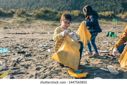 Children Volunteers Picking Up Trash On The Beach