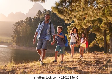 Children Walk By Lake With Parents On Family Hiking Adventure