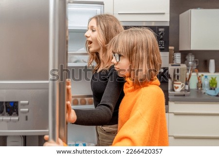 the children are watching the fridge in the kitchen