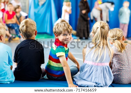 Children watching theater or concert at school. Little kid boy smiling. Kids from back, musical and theatrical performace