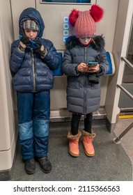 Children Are Watching Videos, Using Mobile Applications In Mobile Phones On City Underground Train. Internet Technology For Streaming Video On Mobile Phone In Underground Public Transportation.