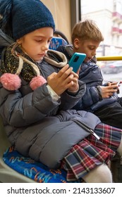 Children Are Watching Videos, Using Mobile Applications In Mobile Phones On City Bus. Internet Technology For Streaming Video On Mobile Phone In Public Transportation. Happy Caucasian Kids Uses Phones