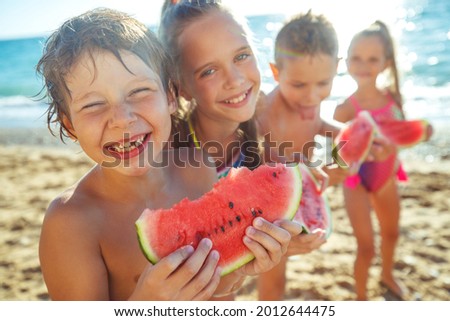 Children with a watermelon at the sea. A group of children have fun playing at the sea. High quality photo