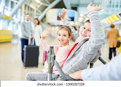 Children Wave Goodbye On The Way On Vacation With Their Parents In The Airport Terminal